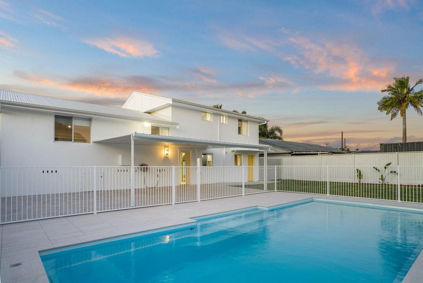 A large white house with a swimming pool in front of it.