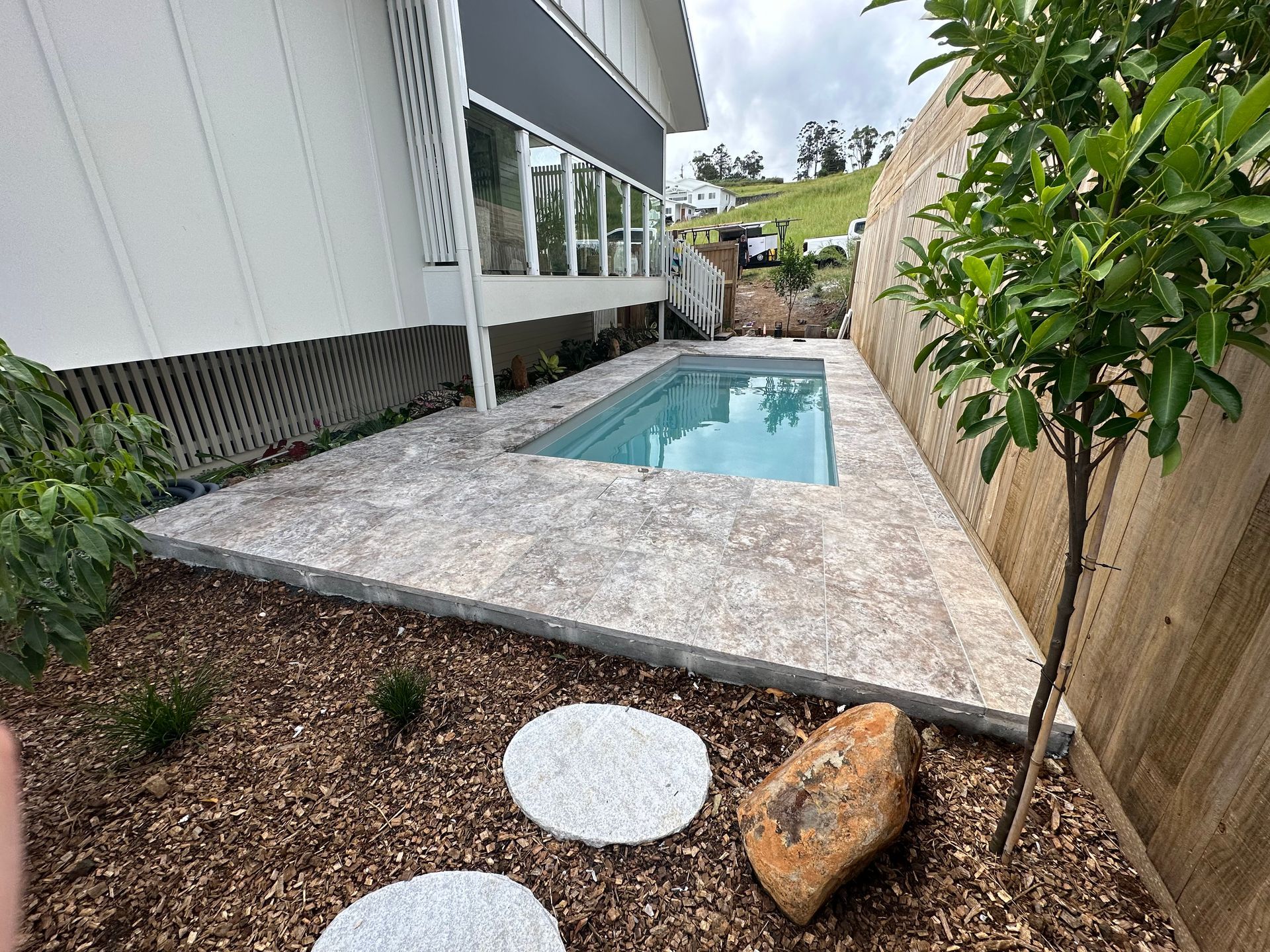 A small, rectangular pool next to a house, with stone pavers and a small tree — Evoke Pools In Lennox Head, NSW