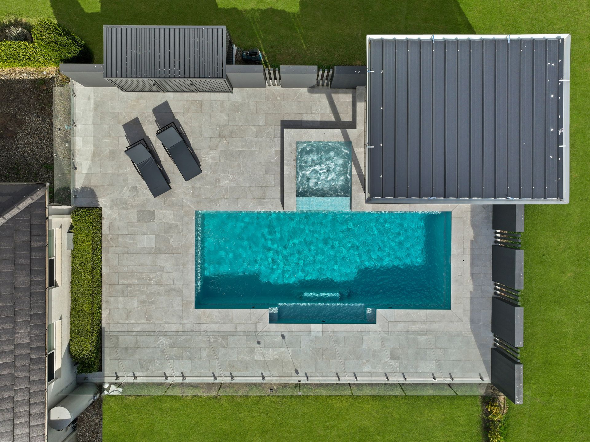 a birds eye view of a pool with sun chairs to the left