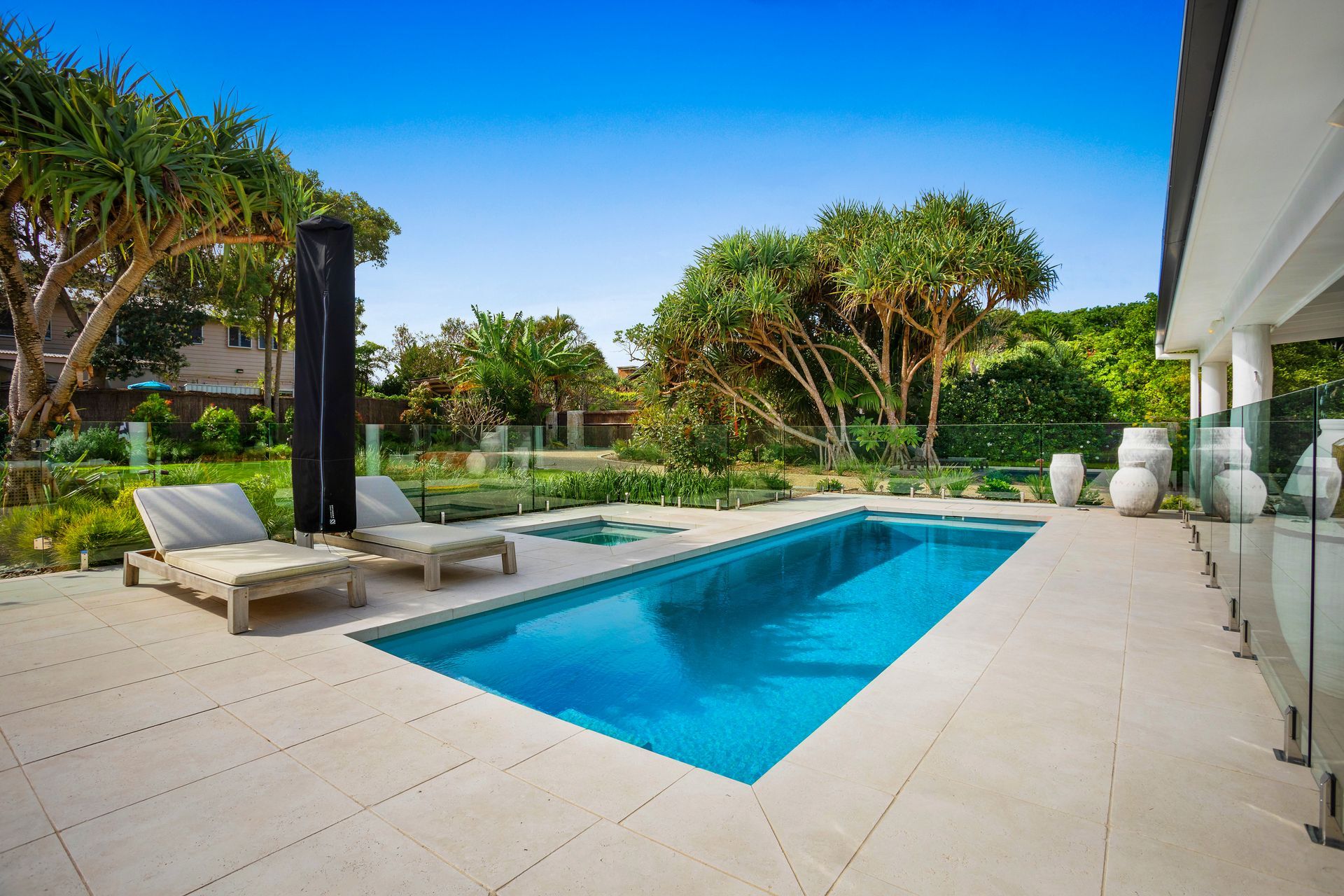Pool with lounge chairs, surrounded by landscaping, on a sunny day — Evoke Pools In Lennox Head, NSW
