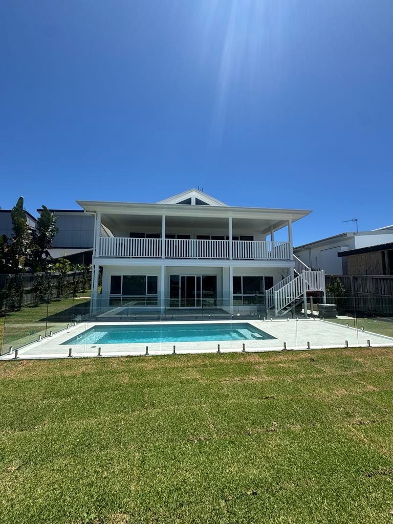 A large white house with a swimming pool in the backyard.