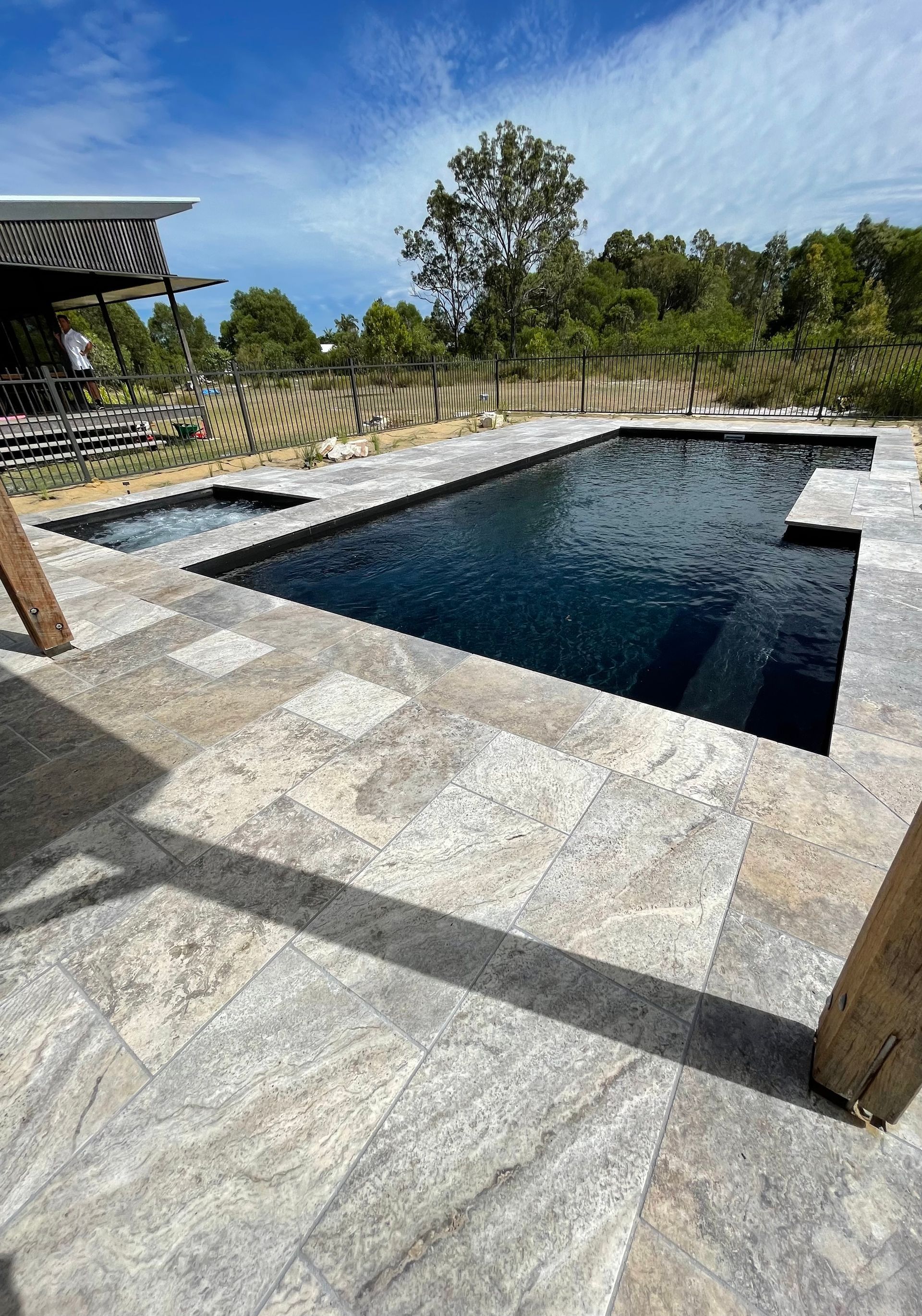 Pool with dark water and light stone patio on a sunny day — Evoke Pools In Lennox Head, NSW