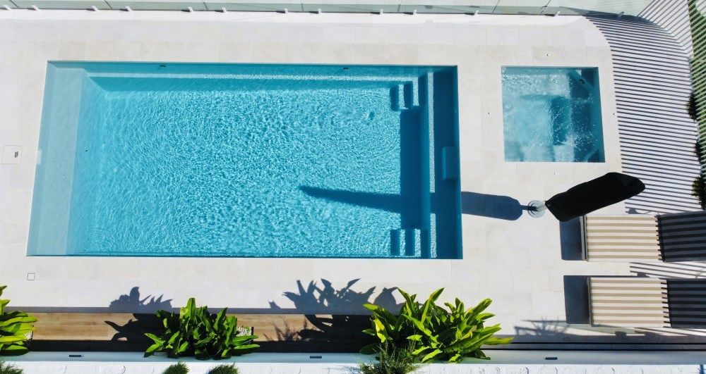 An aerial view of a large swimming pool in the backyard of a house.