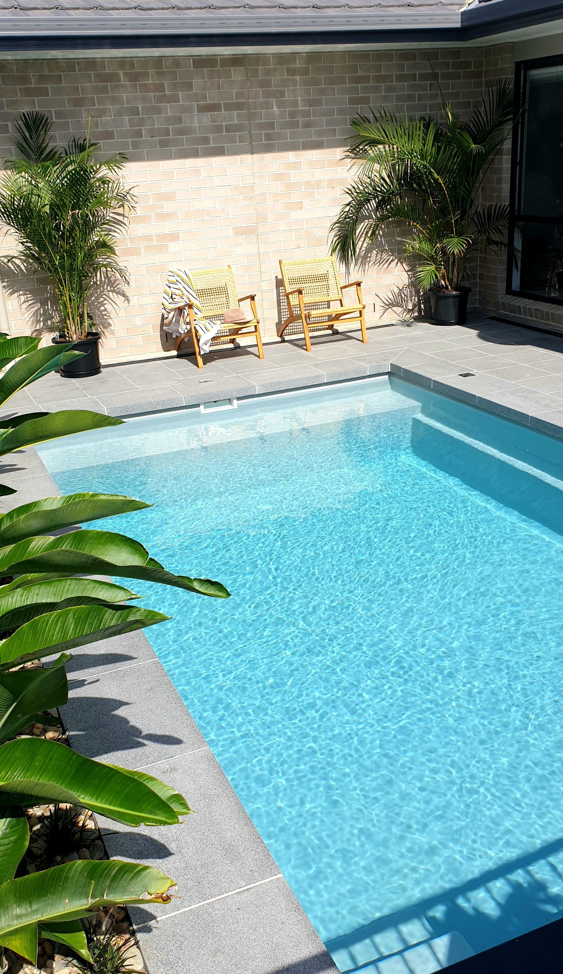 Small swimming pool with blue water, plants, and chairs near a light-colored brick wall — Evoke Pools In Lennox Head, NSW