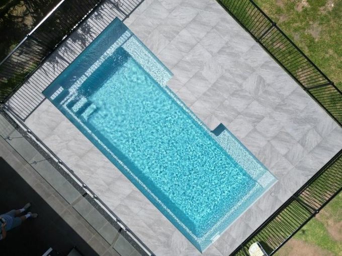 An aerial view of a large swimming pool surrounded by a fence.