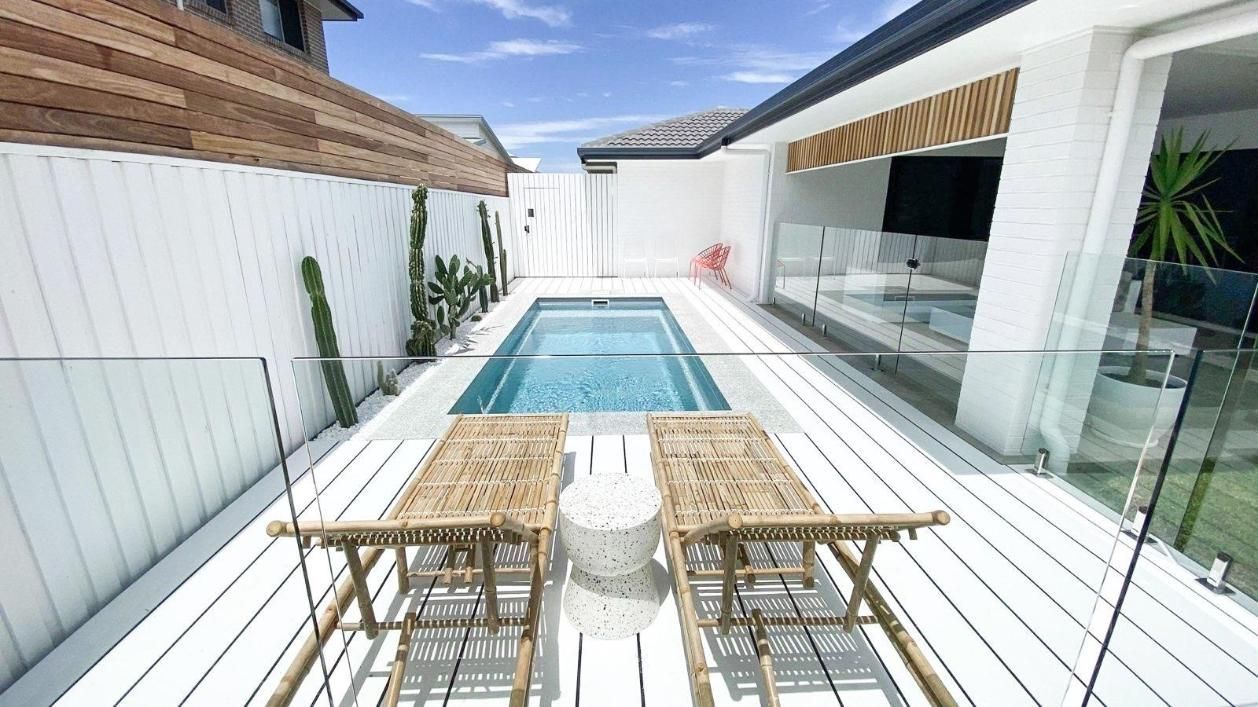 There is a swimming pool in the backyard of a house.