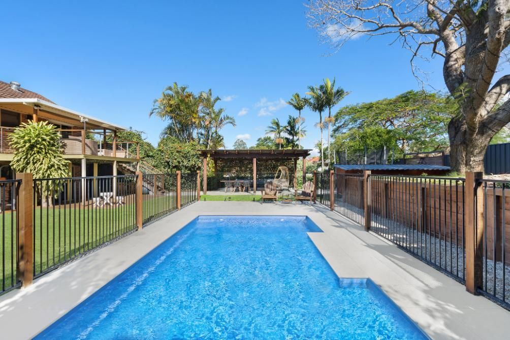 There is a large swimming pool in the backyard of a house.