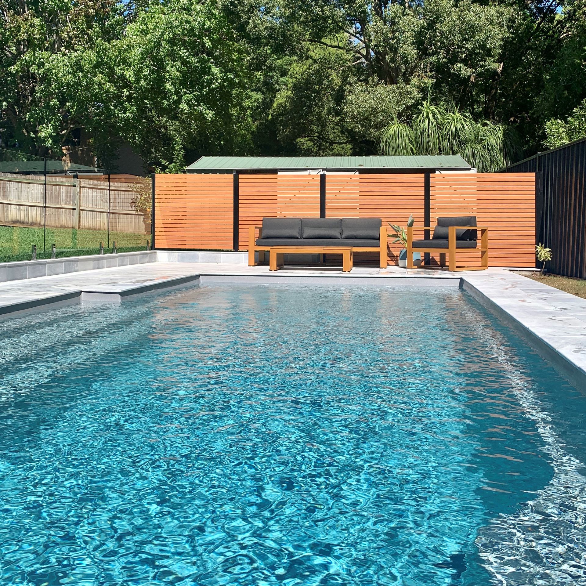 Large concrete pool with wooden deck chairs