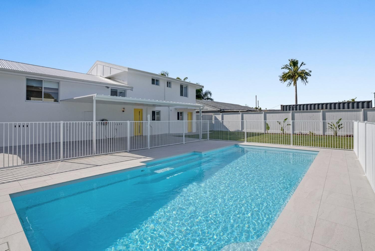 There is a large swimming pool in the backyard of a house.