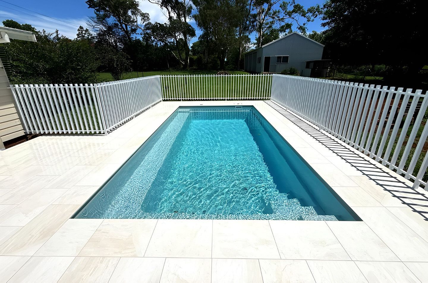 Rectangular Backyard Pool With White Fence