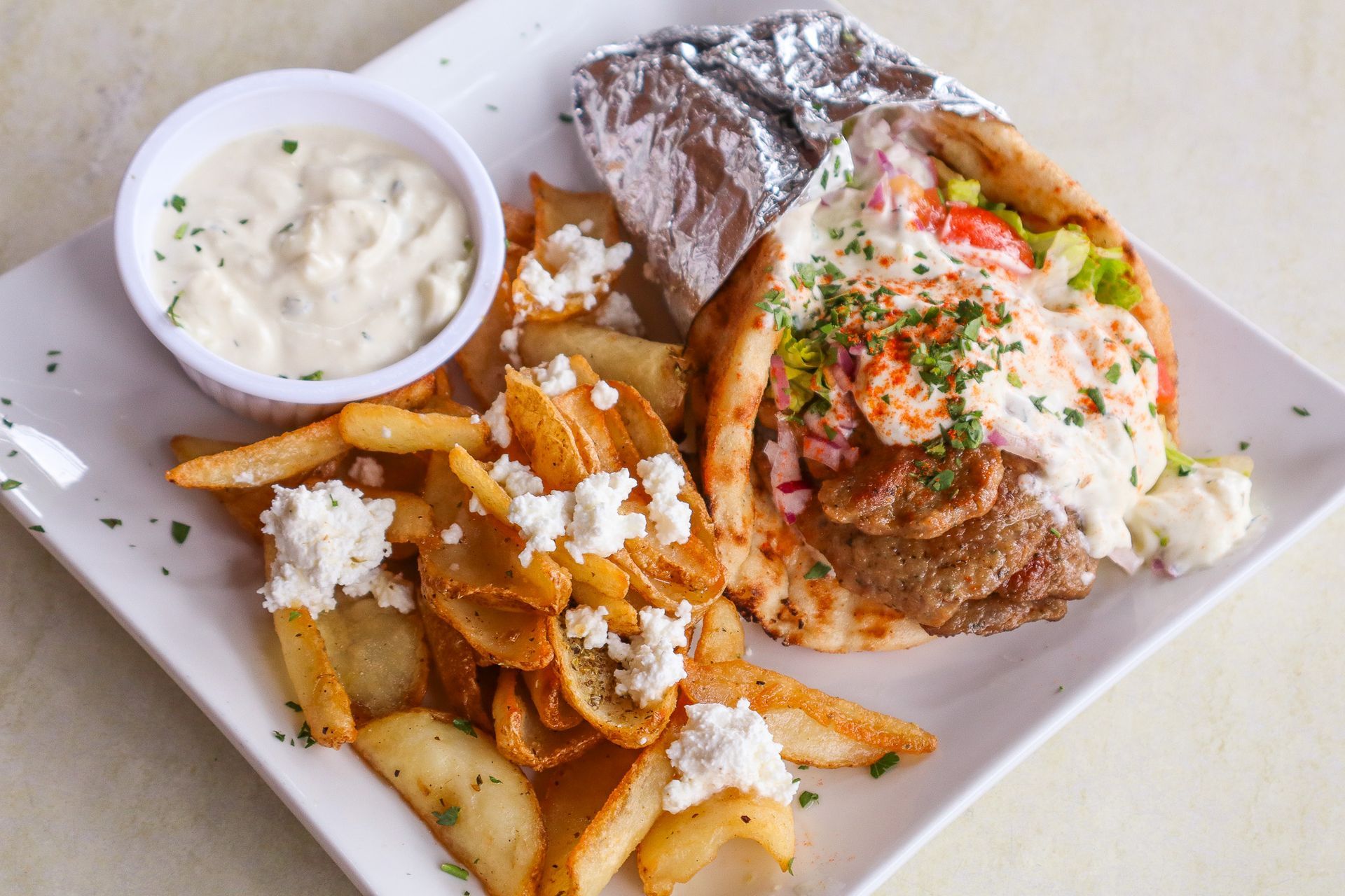 Plate of loaded fries with grilled fish, coleslaw, and a cup of creamy dipping sauce
