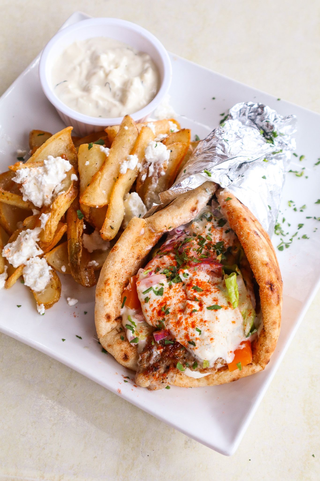 Plated grilled fish with seasoned fries and a small cup of creamy dipping sauce