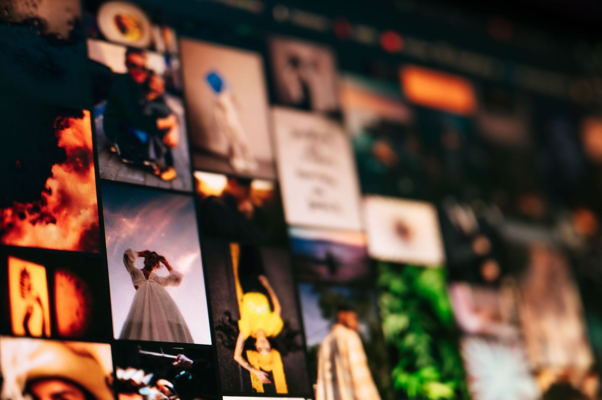Collage of colorful photos pinned on a wall, including portraits and a dancing figure, with a blurred background