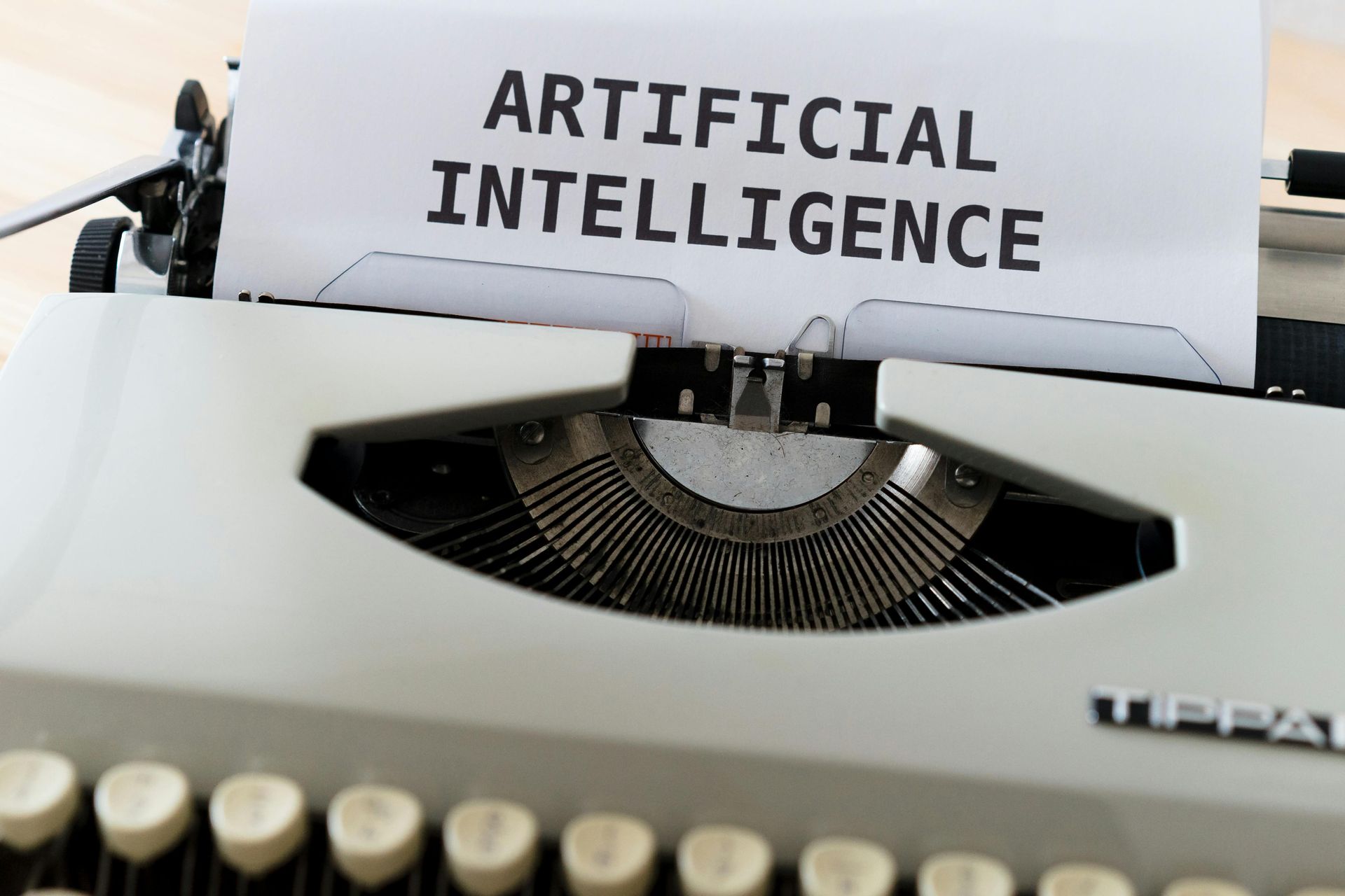 Typewriter with paper reading “ARTIFICIAL INTELLIGENCE”