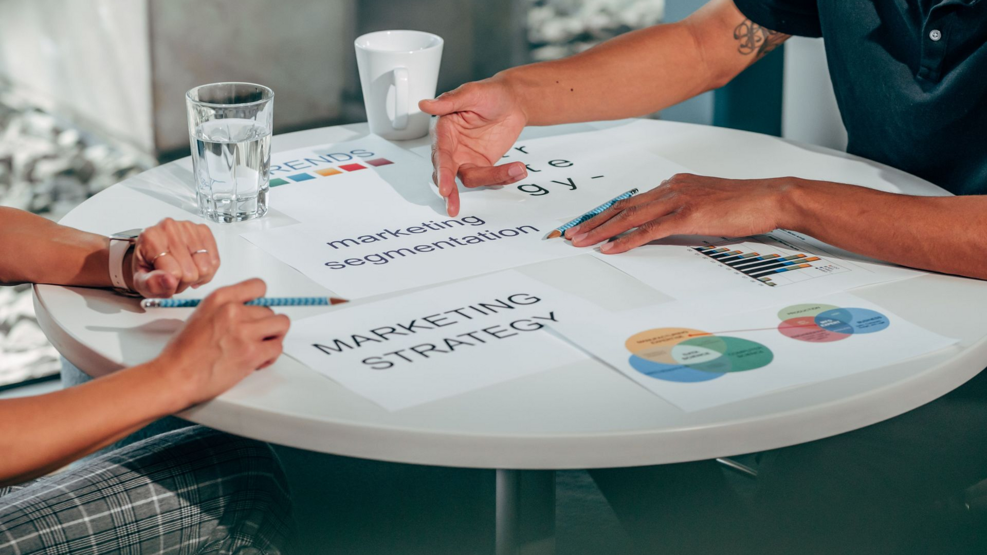 Team discussing charts and notes around a white table in a bright office.