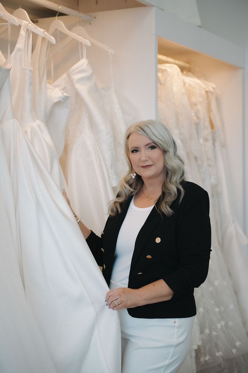 Woman in white wedding gown sitting on antique ornate couch.