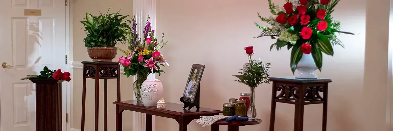 Elegant room with wooden tables displaying potted plants and red floral arrangements on pedestals