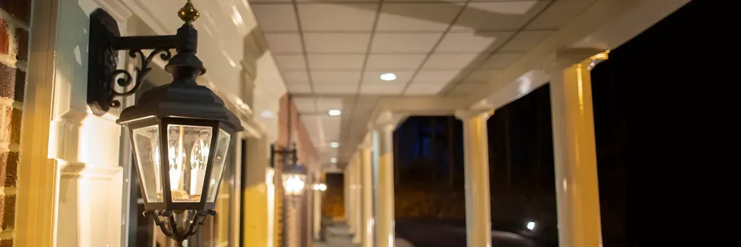 Lanterns hanging under a covered walkway at night, with warm lights and columns receding into the distance