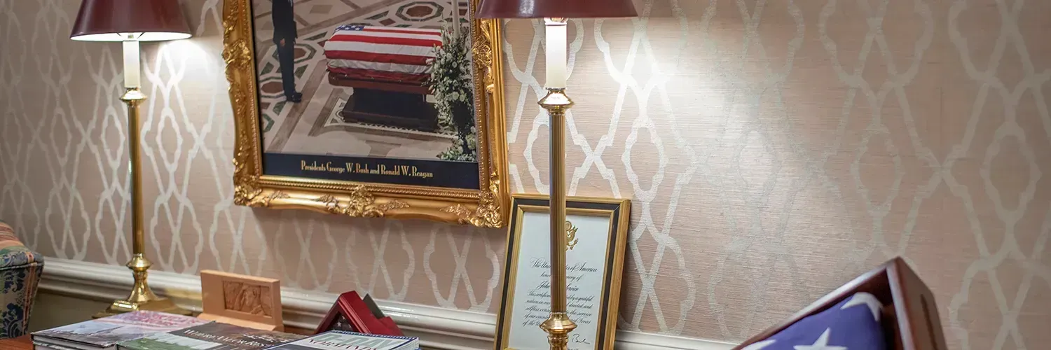 Framed gold portrait and decorative candlesticks on a patterned wall in a formal room