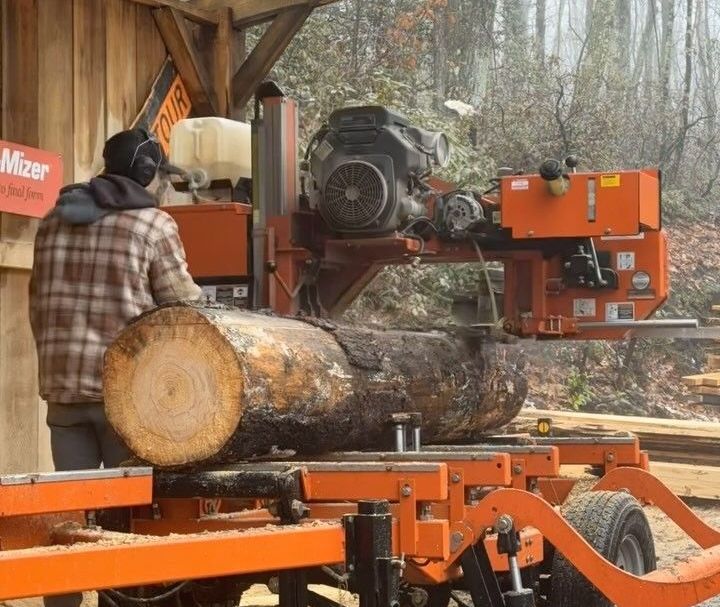 A man is cutting a log in front of a sign that says mixer