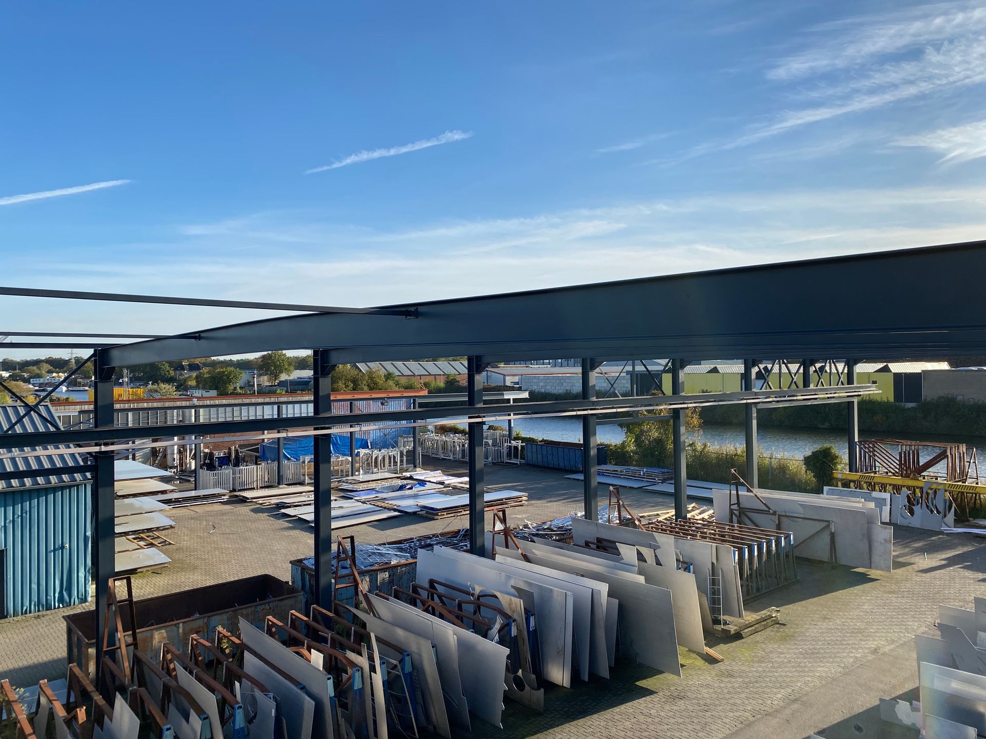 Een opslagterrein voor natuurstenen platen in de openlucht, met rijen rechtopstaande natuurstenen platen onder een metalen frame.