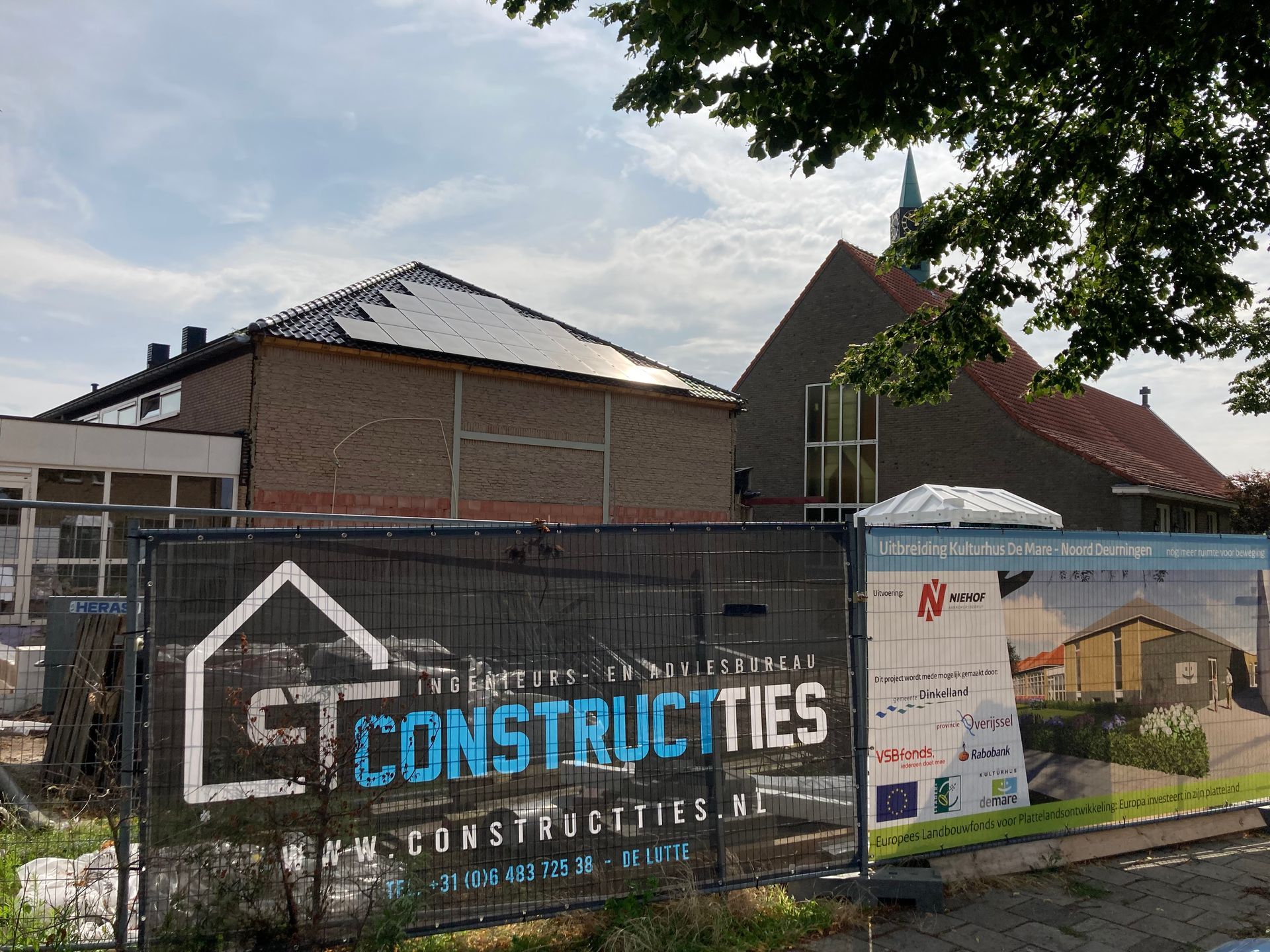Bouwterrein met een tijdelijk zwart hekwerk met het logo van 