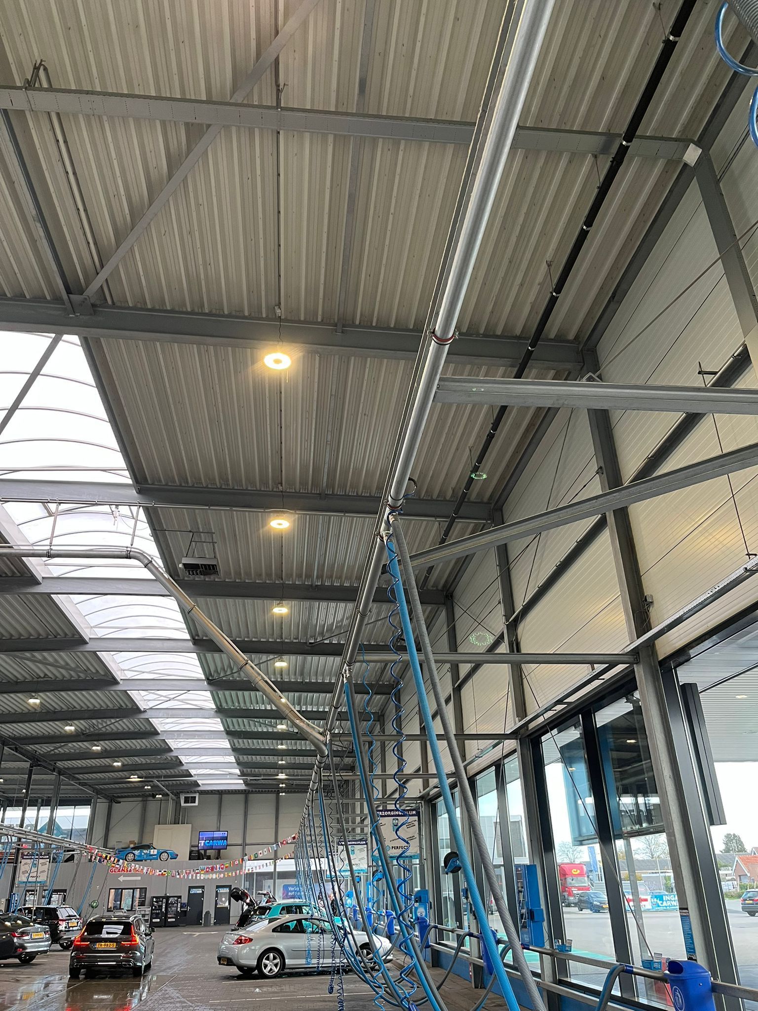 Het interieur van een autowasstraat met een opvallende blauwe rails boven het hoofd en mechanische apparatuur, gezien vanuit een laag perspectief.