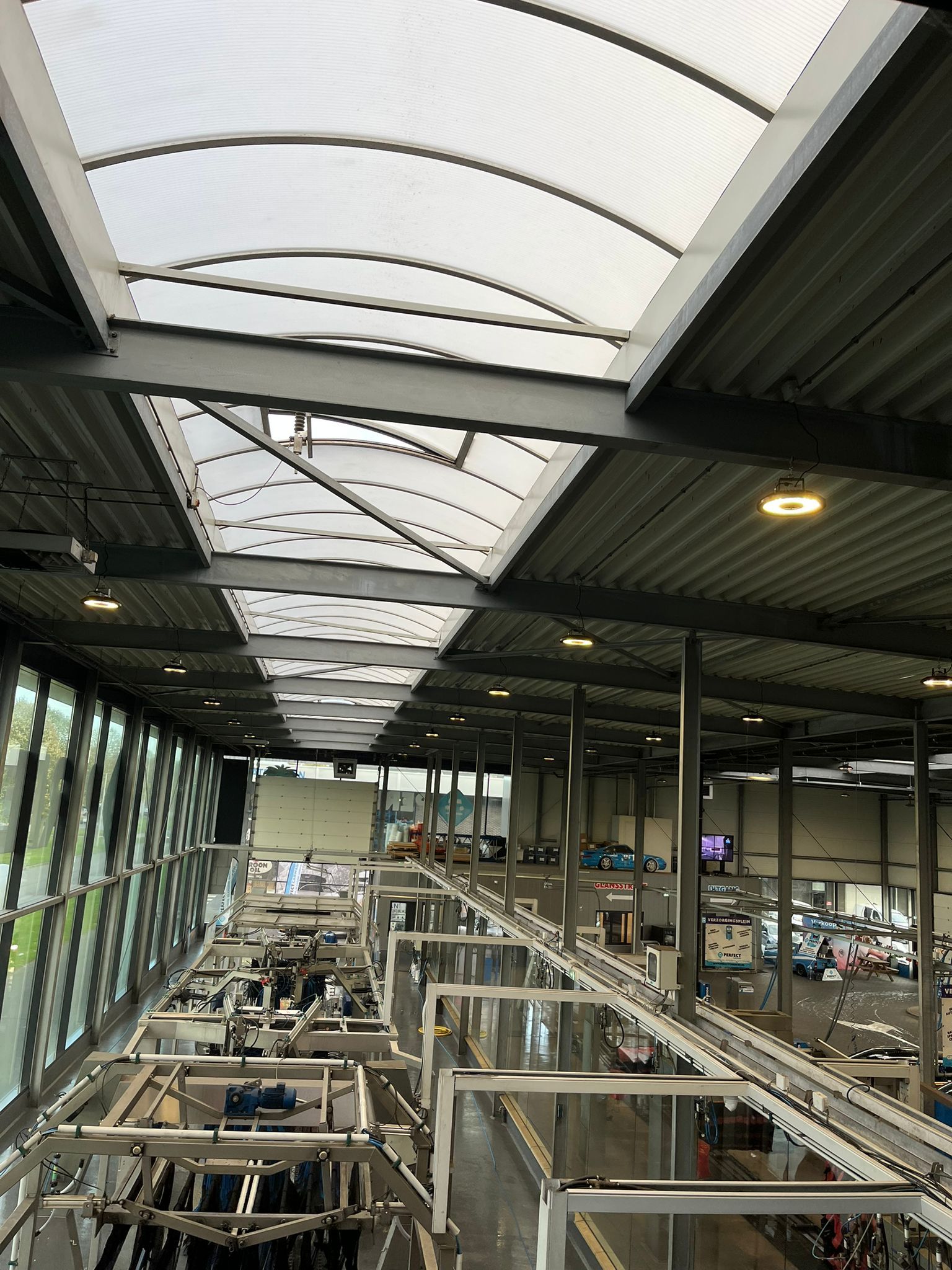 Een hoog perspectief van een moderne industriële productiefaciliteit met grote ramen, dakramen en assemblagelijnen voor voertuigen.