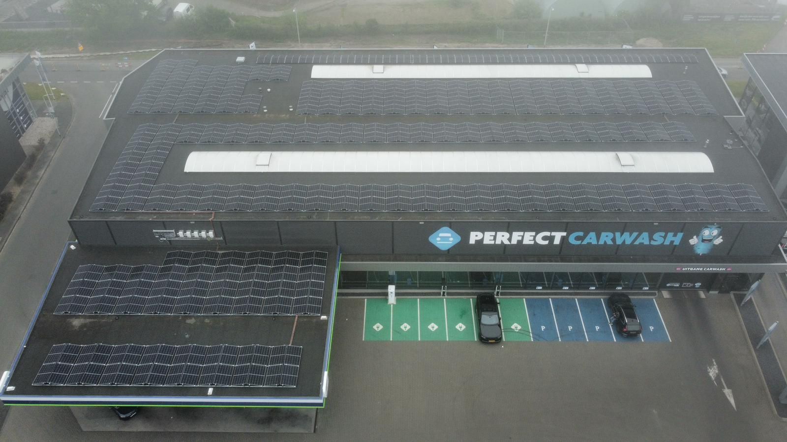 Een luchtfoto van een donker gebouw met zonnepanelen op het dak, met het opschrift 