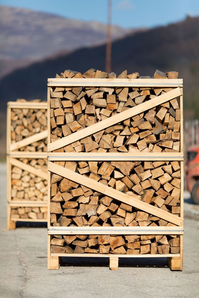 Una catasta di legna è accatastata una sopra l'altra su pallet di legno.