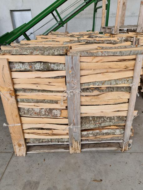 Un pallet di legno è appoggiato a terra accanto a un nastro trasportatore verde.