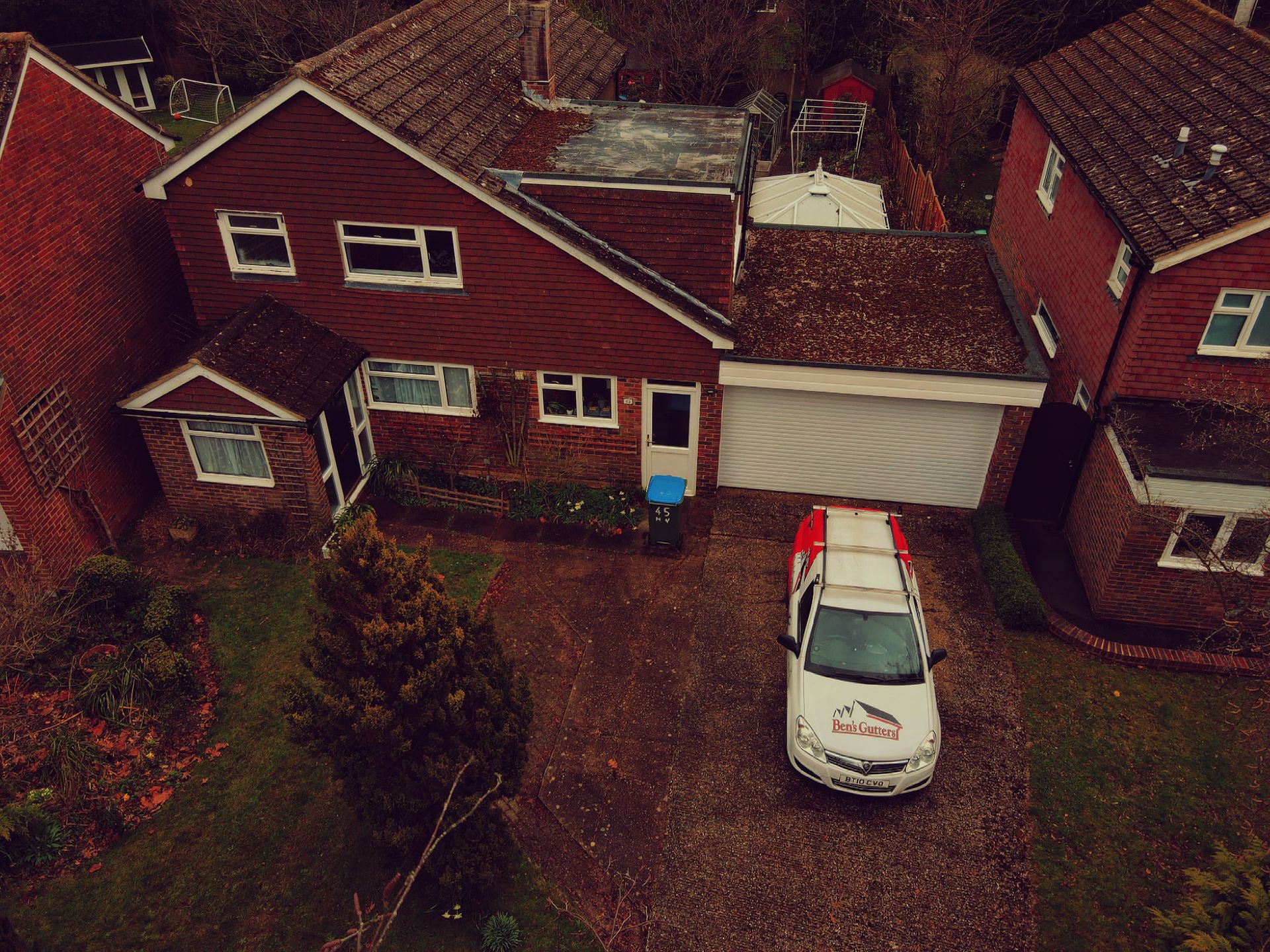 Red brick house with a white service van in the driveway. Overcast sky.