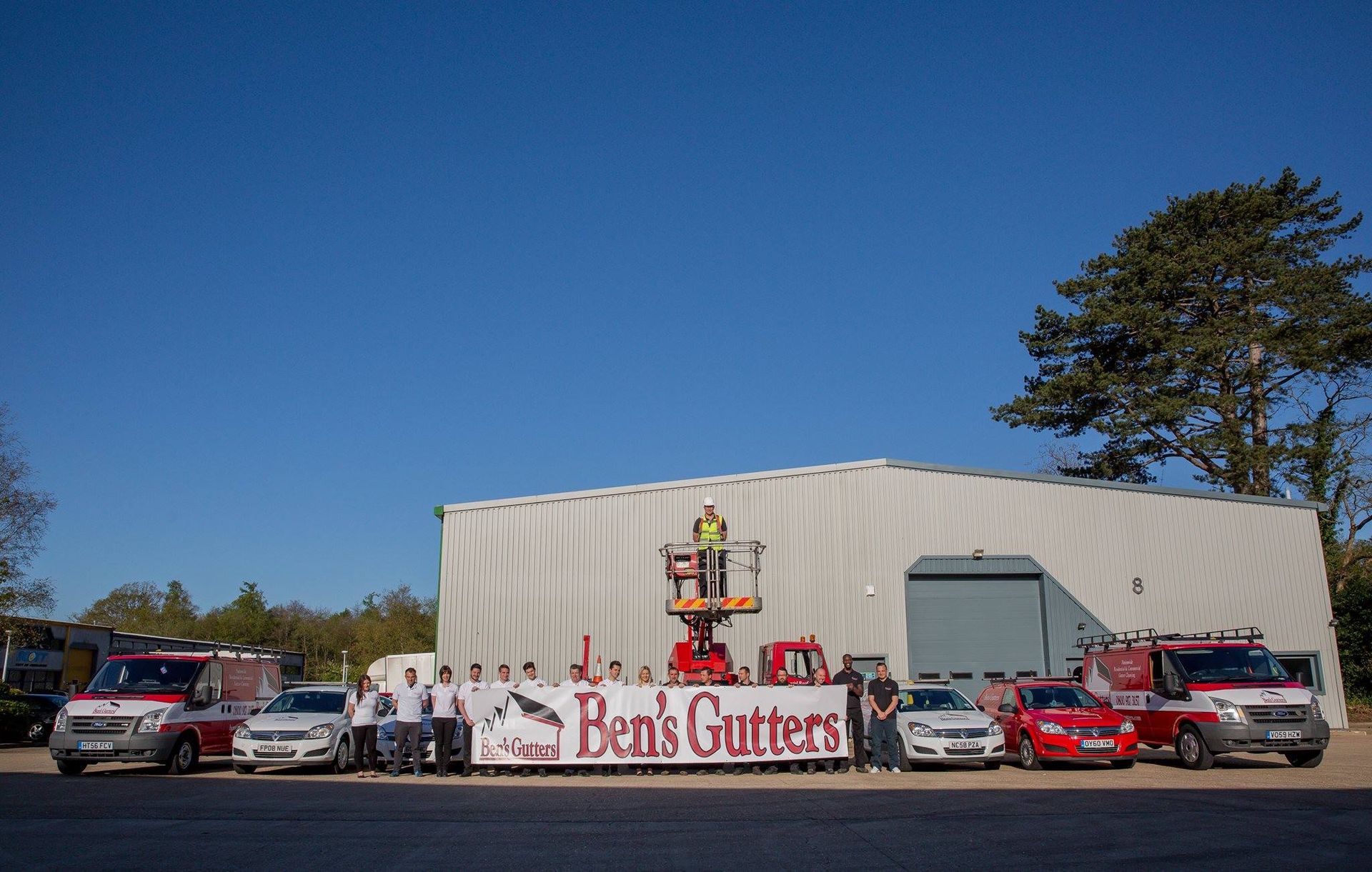 Group of people and vehicles outside a building; a sign reads 