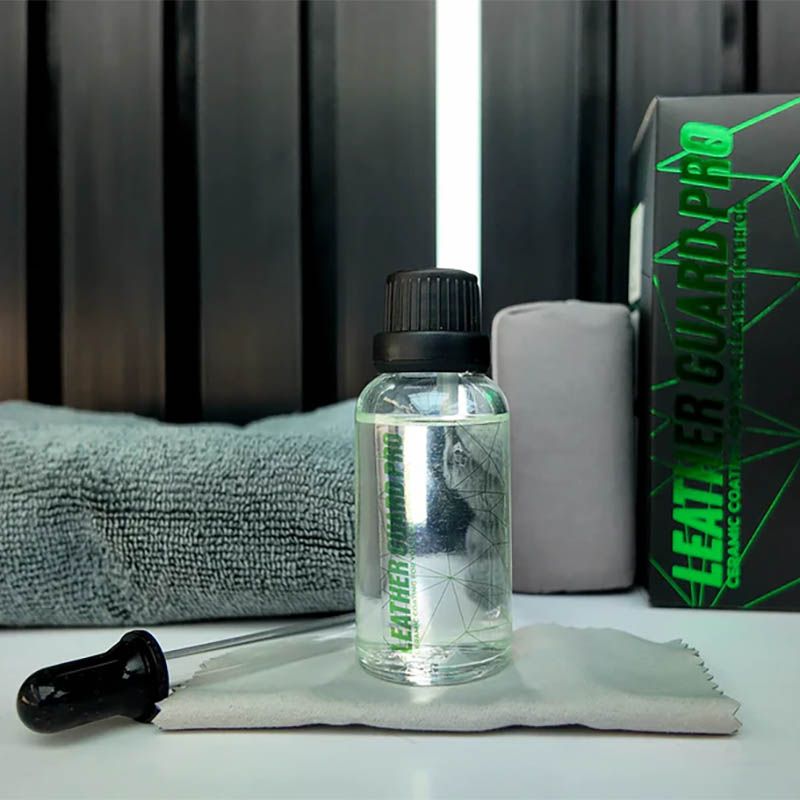 Clear liquid bottle with black cap on a towel beside a gray soap bar and green packaging.
