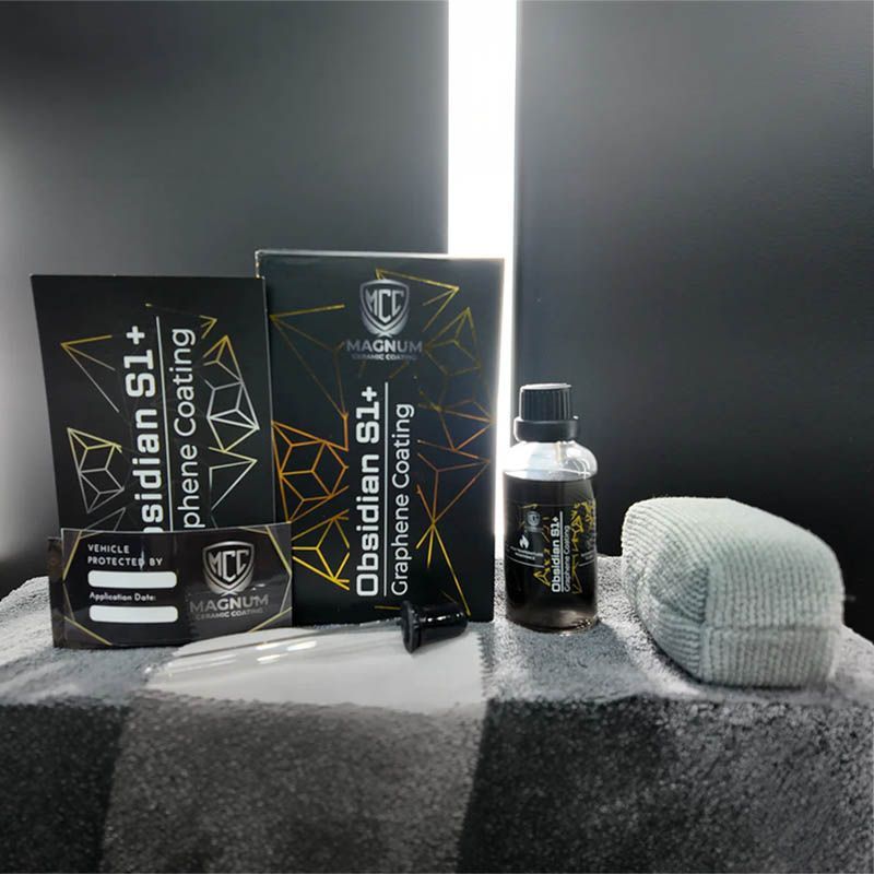 Black skincare product set with box, bottle, and white sponge on a dark surface, lit by a bright backlight