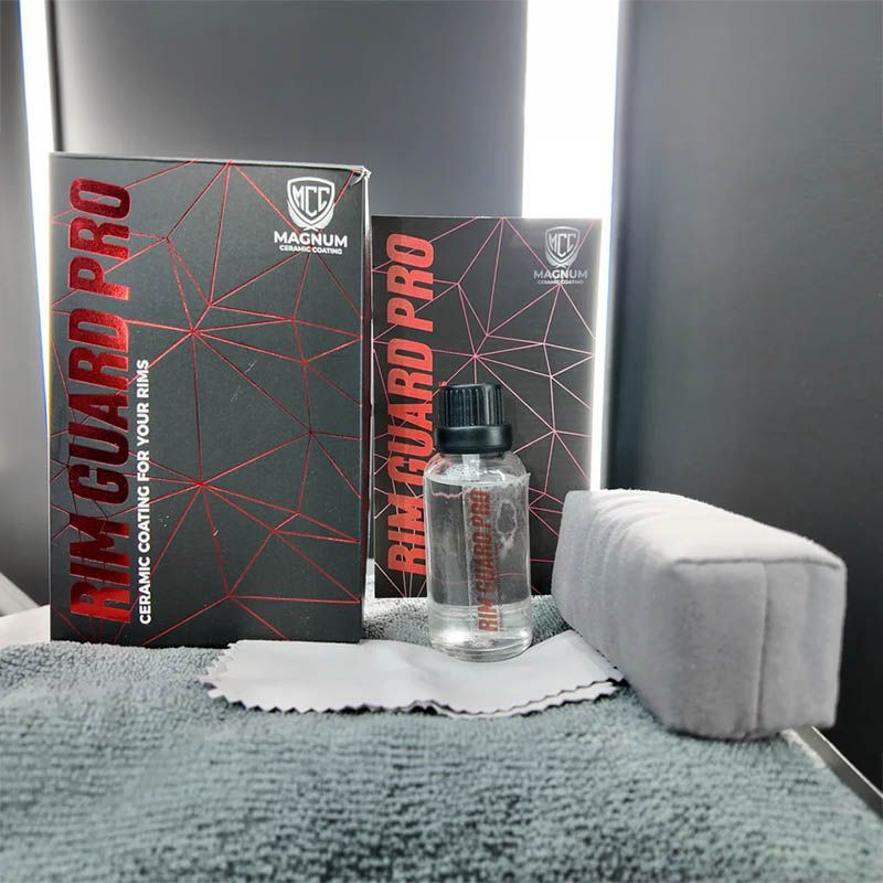 Black-and-red MacGard Pro boxes with a clear bottle on a gray towel and white block set against a gray background