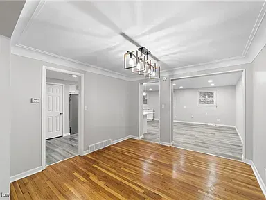 Empty dining room with hardwood floors, gray walls, and a modern chandelier