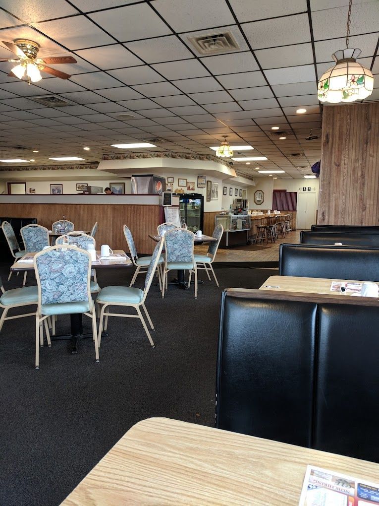 Empty restaurant dining area with tables, chairs, booths, and ceiling lights