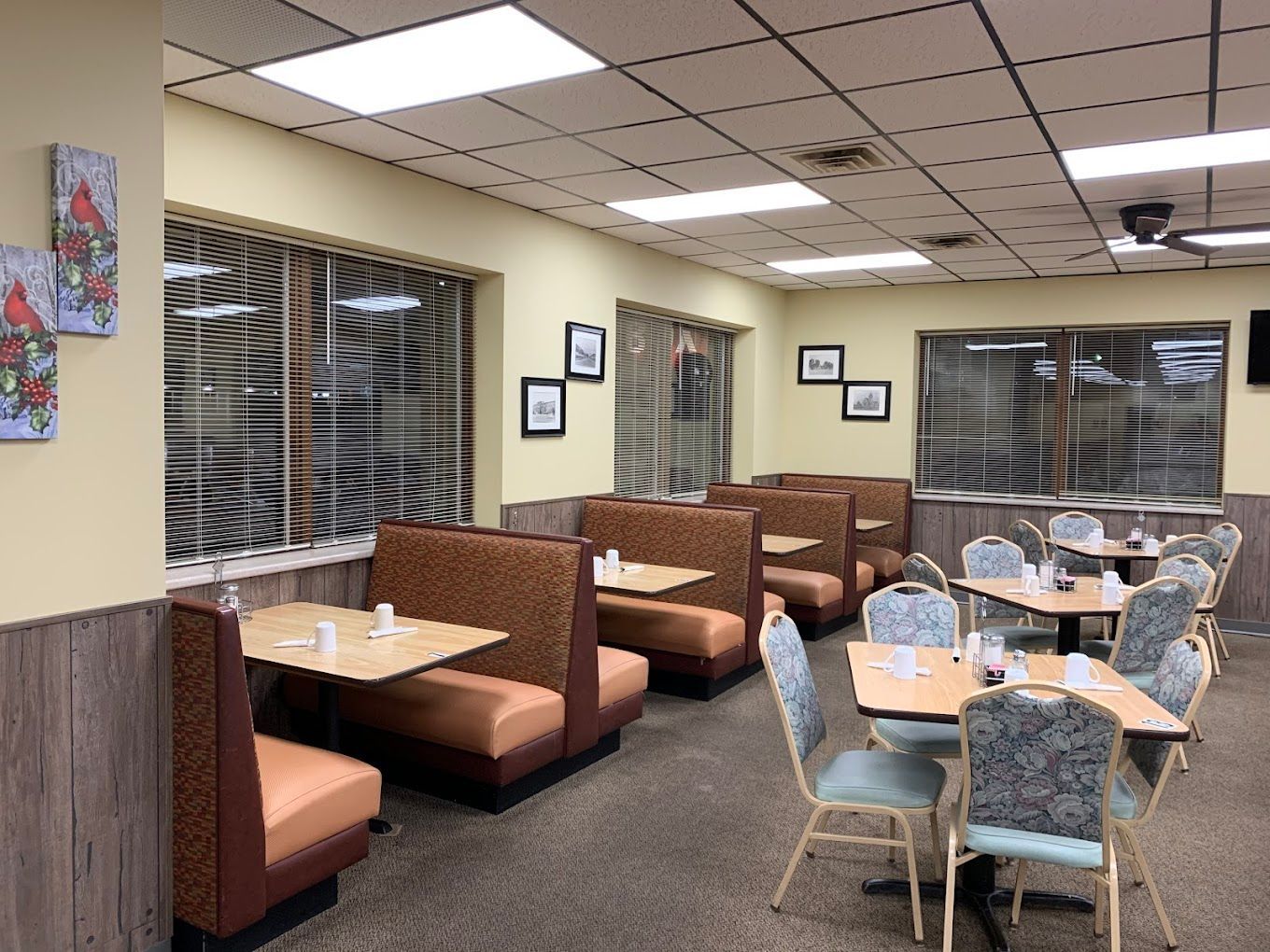 Empty restaurant dining area with booths, tables, blue chairs, and warm ceiling lights