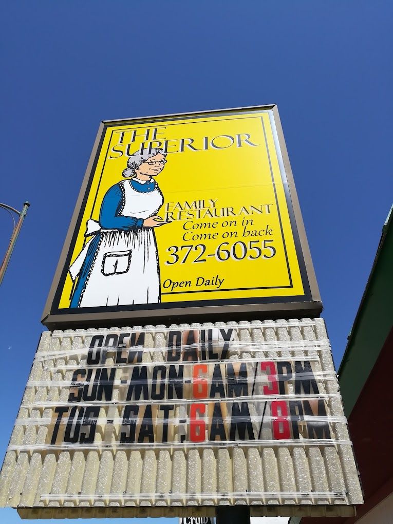 Yellow billboard with a painted man holding a marker against a blue sky.