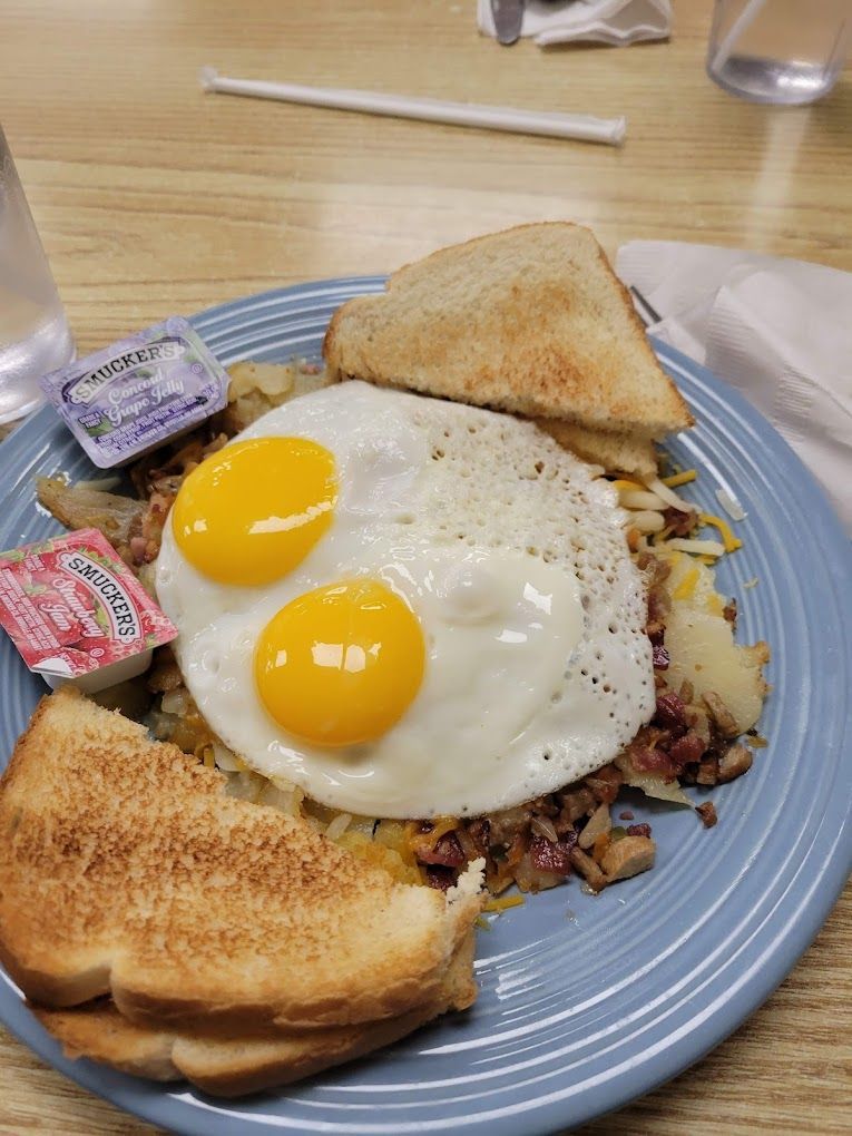 Breakfast plate with two sunny-side-up eggs, toast, and hash browns on a blue dish