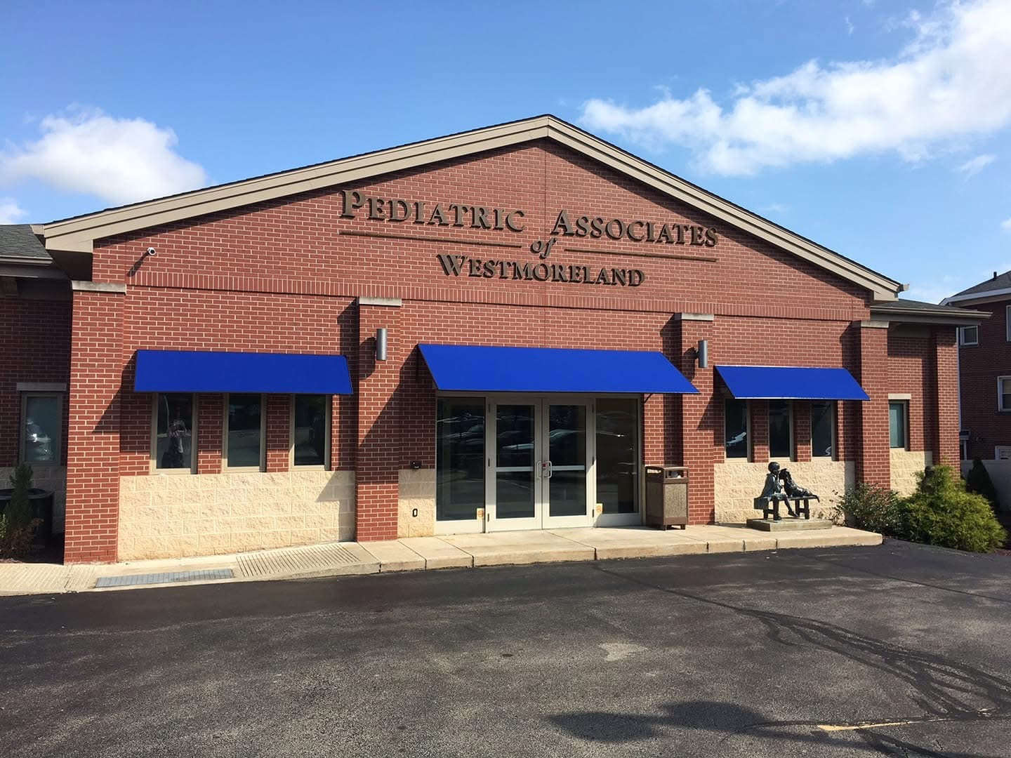 A brick building with blue awnings on the front of it with Pediatric Associates of Westmoreland on the front of the building.