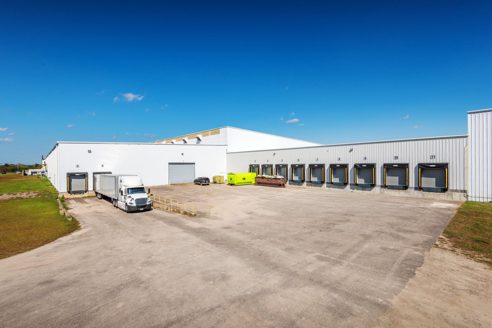 A warehouse with trucks parked in front of it on a sunny day.