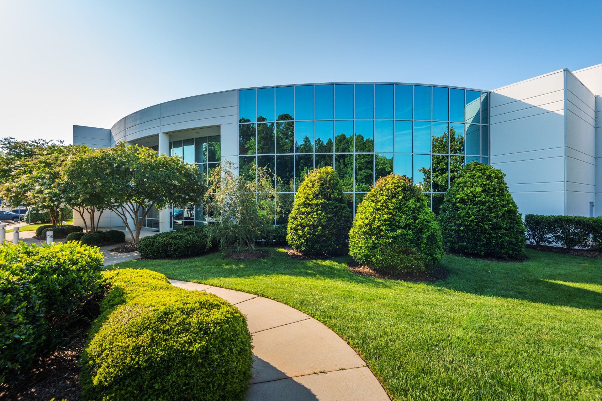 A large white building with a lot of windows and bushes in front of it.
