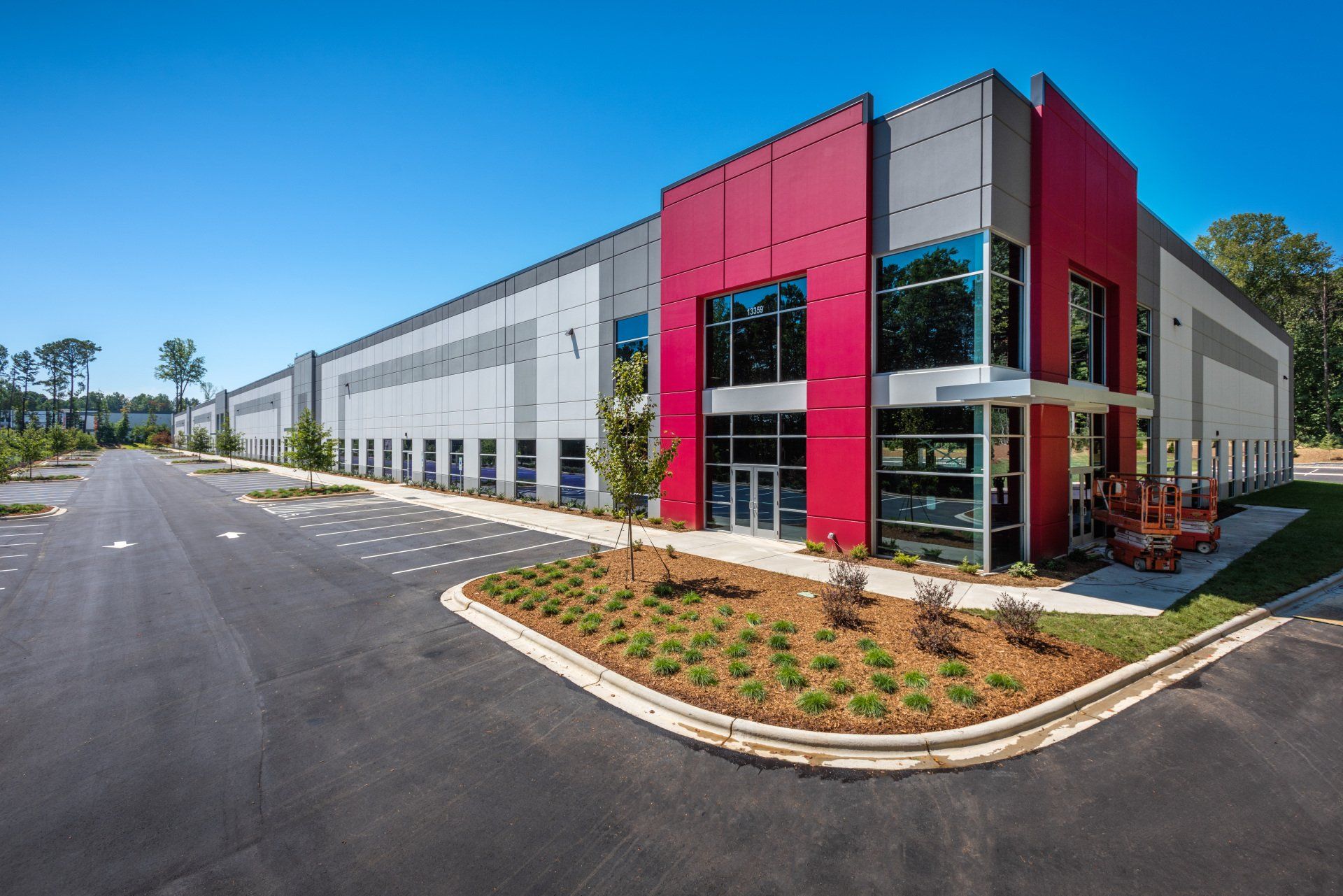 A large red and gray building with a lot of windows is sitting next to a road.