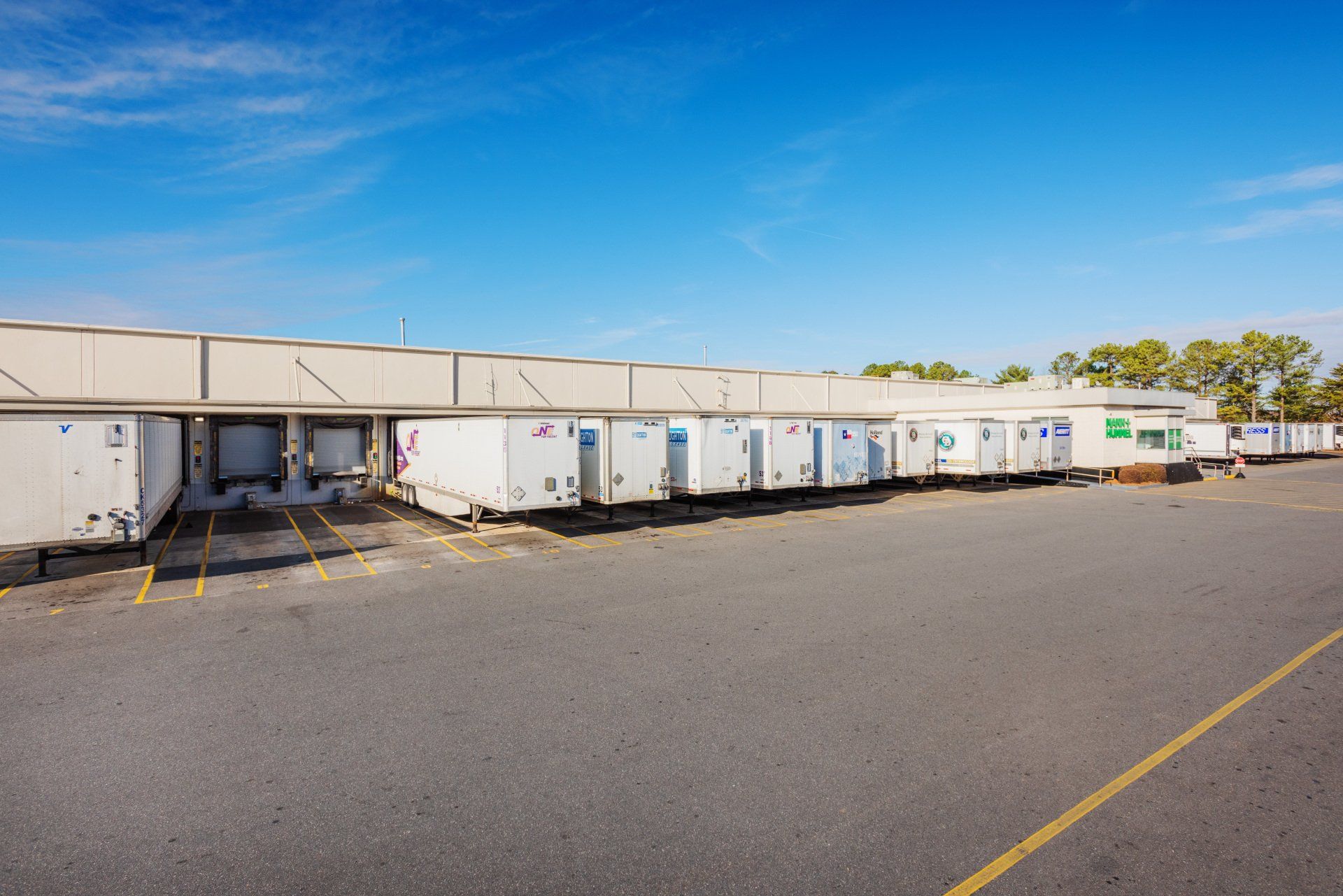 A row of white trailers are parked in front of a building.