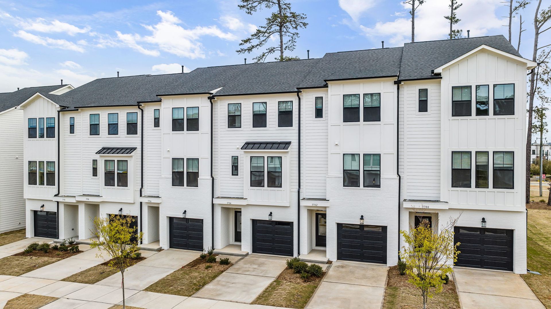 A row of white houses with black garages in a residential area.