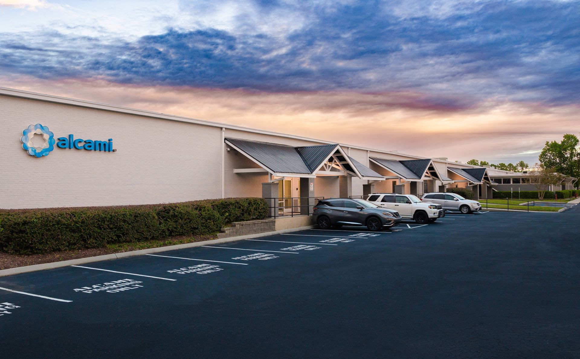 A row of cars are parked in front of a building.