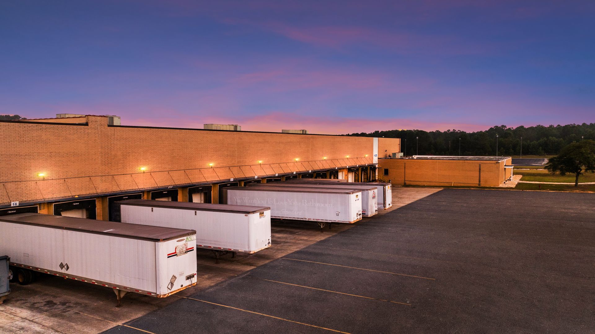 A row of trailers are parked in front of a building.