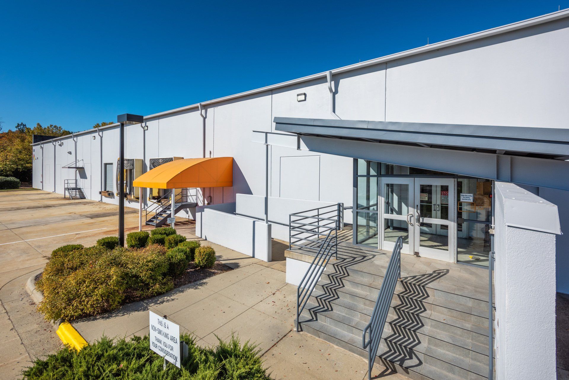 A large white building with an orange awning and stairs leading to it.